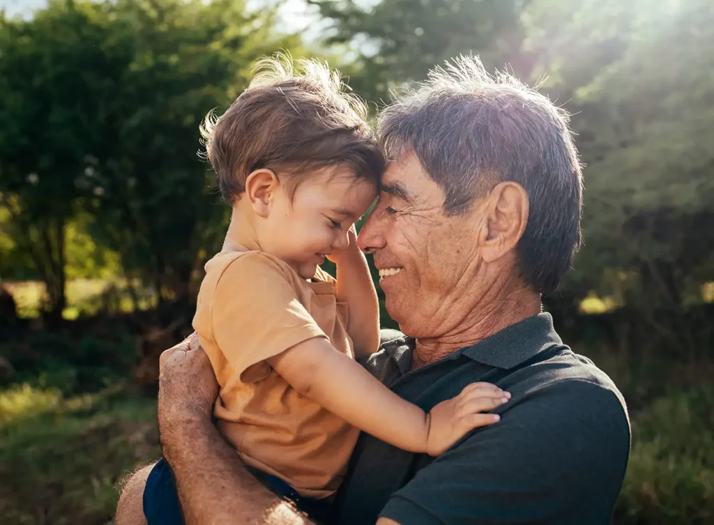 elderly man hugging his grandchild while feeling the financial freedom of retirement annuity plans