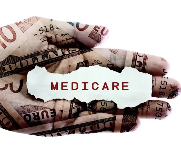 This is a photo of a hand showing different forms of currency wrapped around the hand with the word “Medicare” in the center.